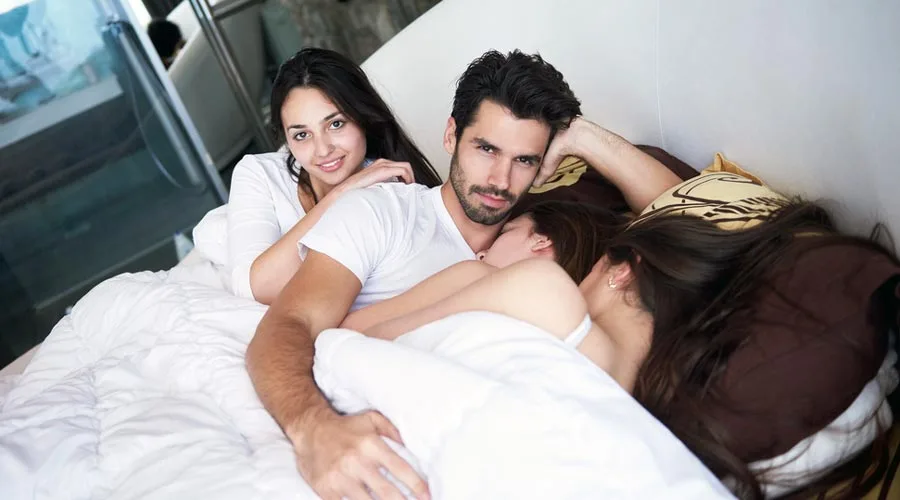 Sex addicted man in bed with three beautiful woman